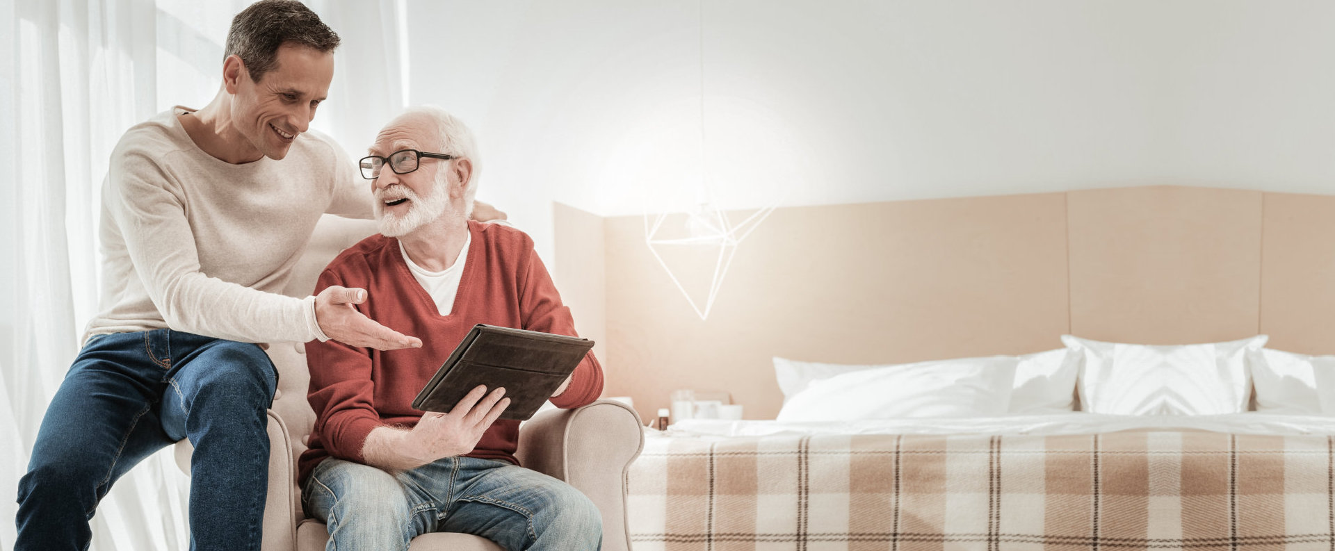 elderly man browsing his tablet with another man