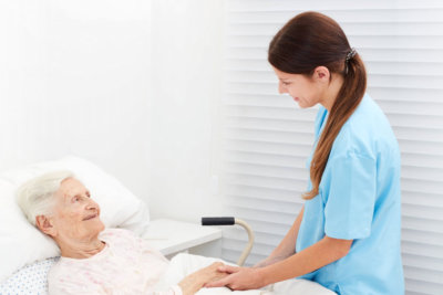 caregiver visiting elderly woman in bed