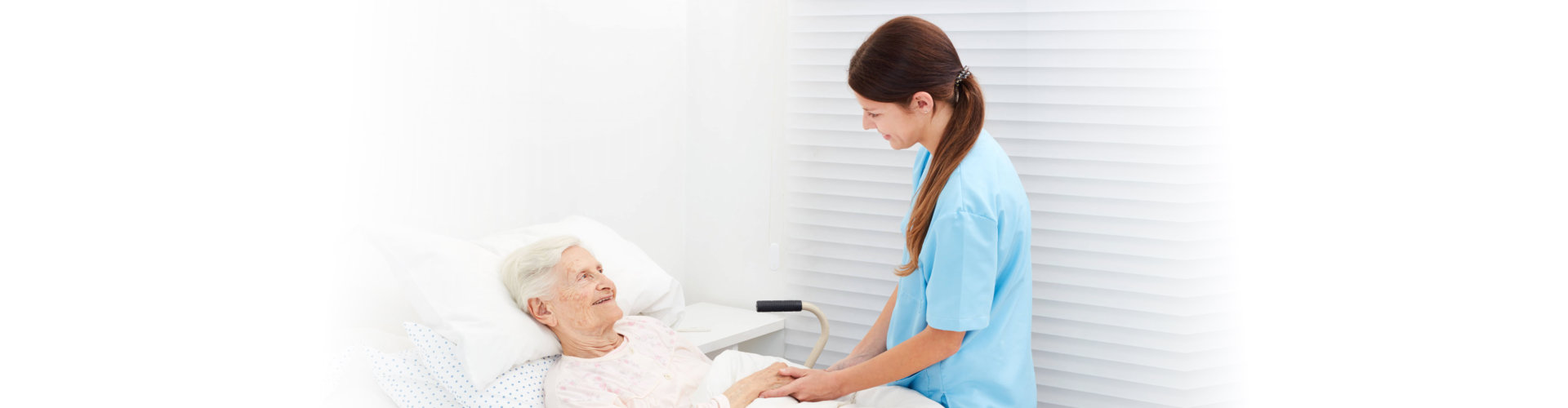 caregiver visiting elderly woman in bed